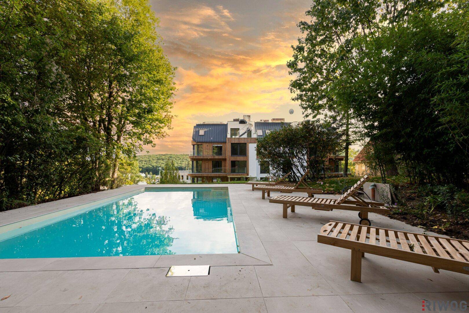 Großer Außenpool mit Liegefläche und umgebendem Garten, ideal für Entspannung im Freien.