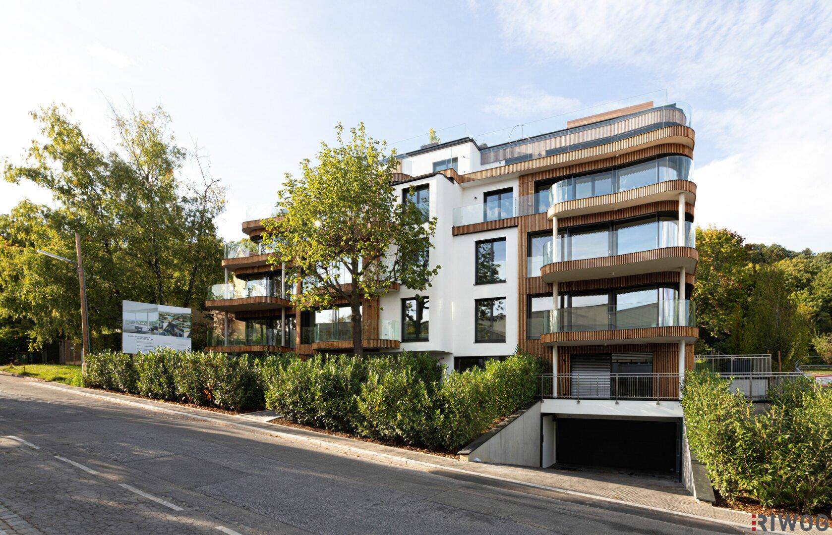 Luftaufnahme eines modernen Wohnkomplexes mit grünen Dächern und Balkonen, umgeben von Natur.