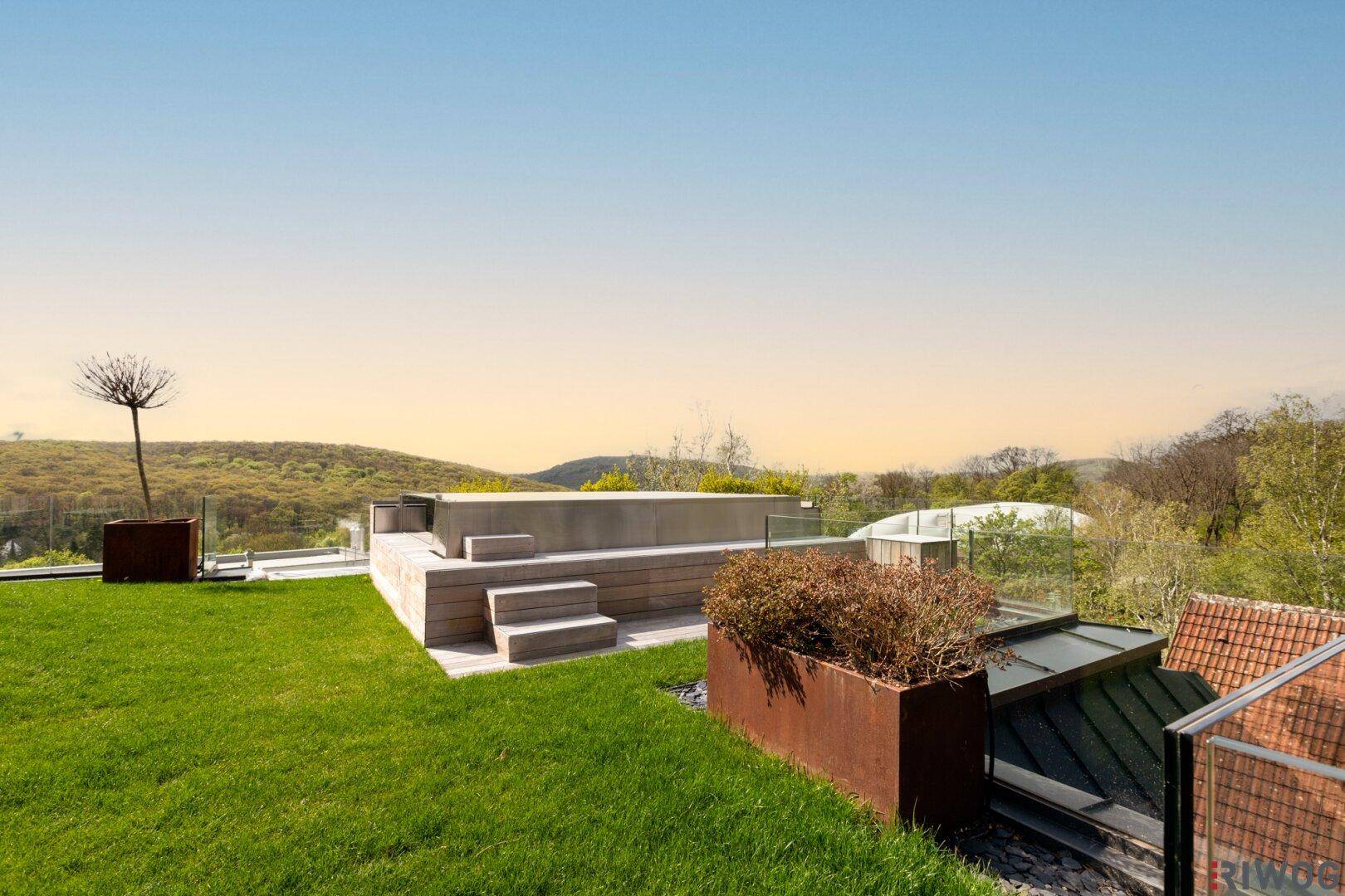Grüne Dachterrasse mit Holzpodest und Glasgeländer, bietet einen idyllischen Blick auf die Natur.