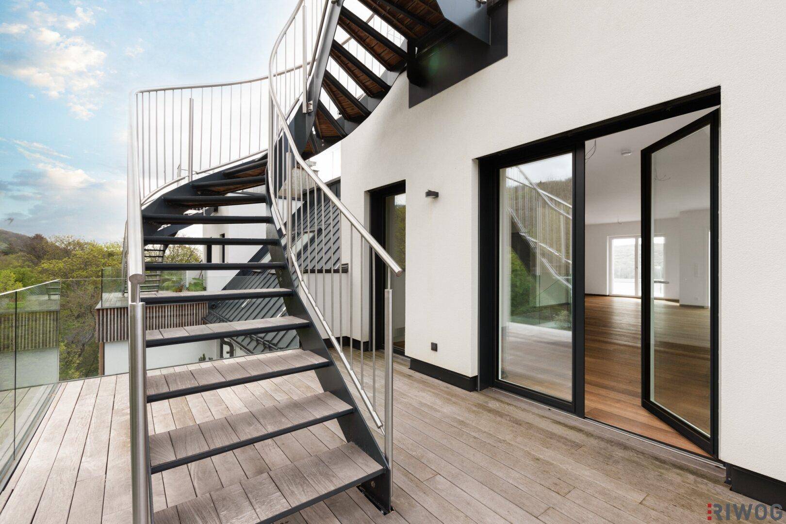 Außentreppe aus Metall und Holz führt zu einer weiteren Ebene, umgeben von moderner Architektur.