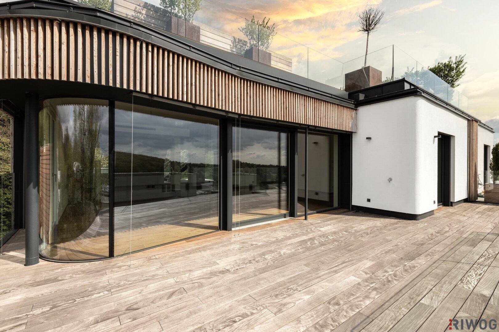Elegante Holzterrasse mit geschwungener Glasfront und Holzlamellen, bietet einen stilvollen Außenbereich.
