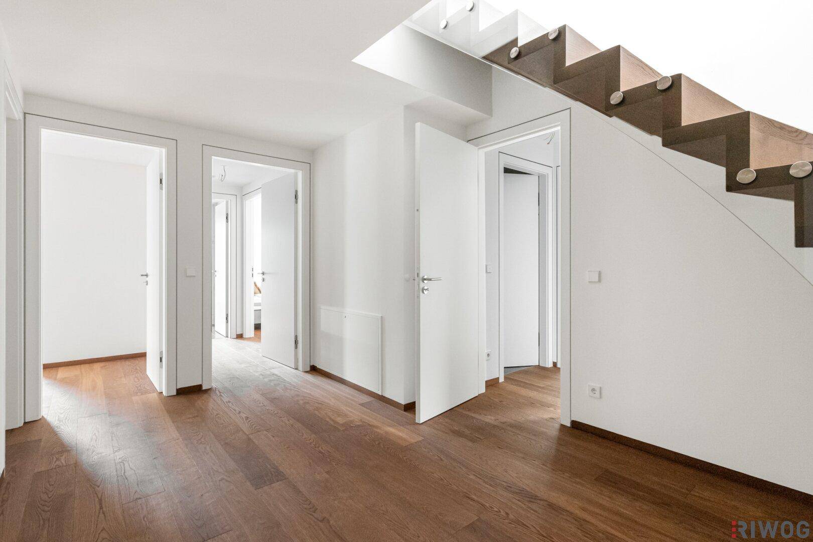 Schlafzimmer mit großen Fensterfronten und Holzboden, bietet einen schönen Blick ins Grüne.