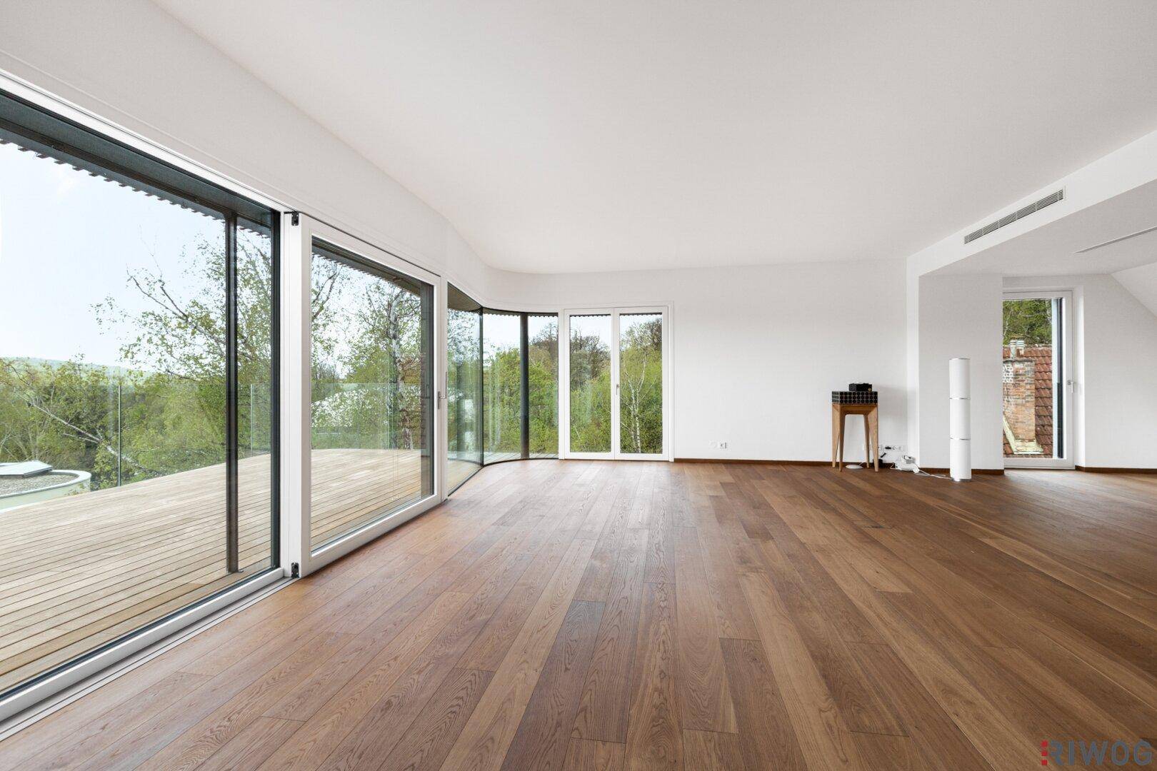 Helles, geräumiges Wohnzimmer mit großen Glasfronten und Holzboden, bietet Zugang zur Terrasse.