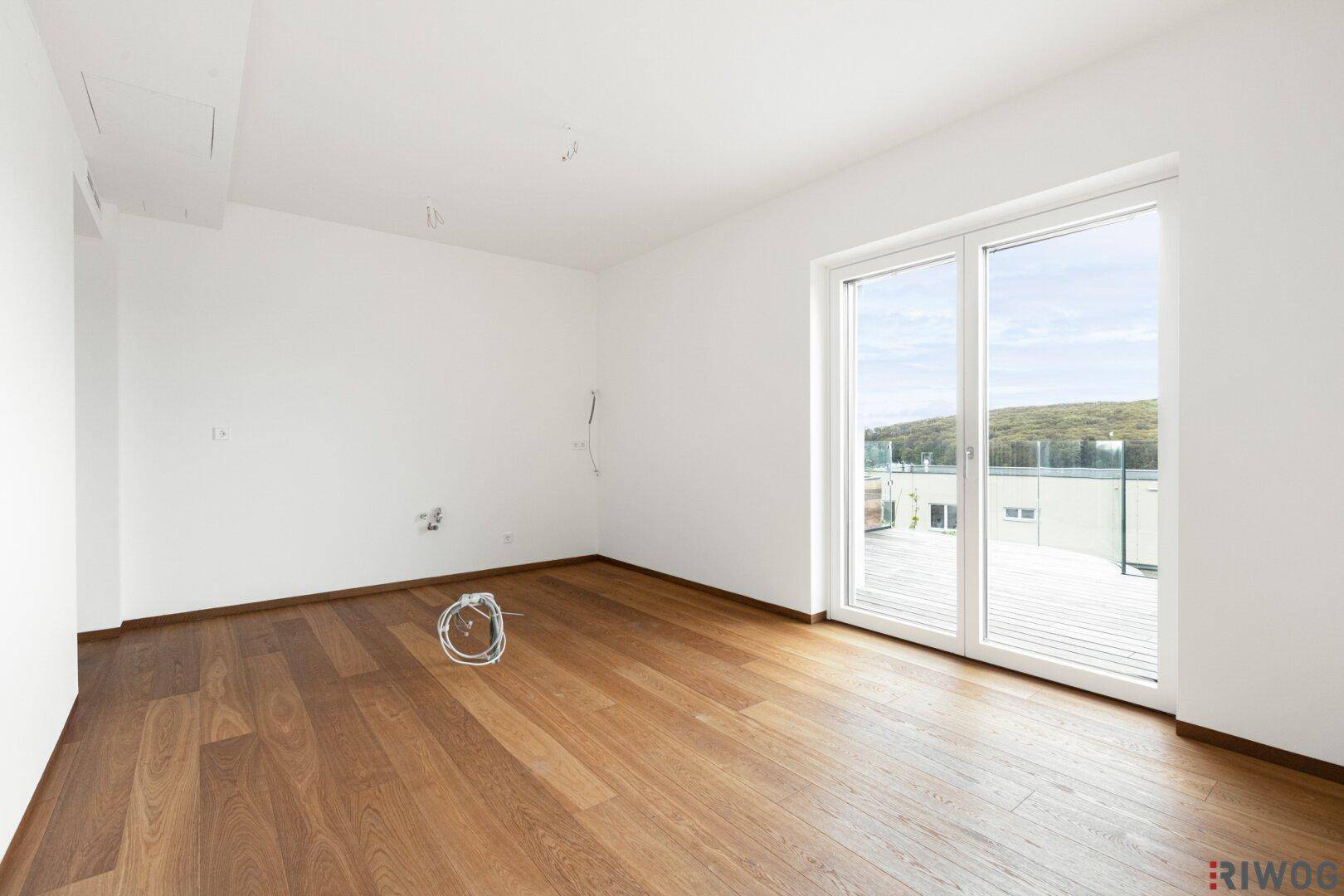 Heller Raum mit Holzboden und Zugang zu einer Außenterrasse, ideal für individuelle Gestaltung.