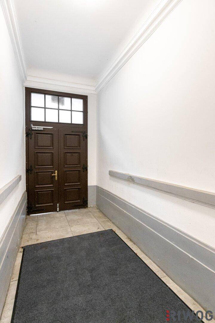 Eingangsbereich mit dunkler Holztür, Fliesenboden und Rampe für barrierefreien Zugang.