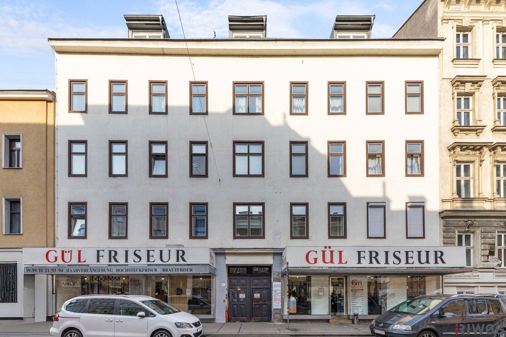 Historische Fassade eines Mehrfamilienhauses mit Geschäften im Erdgeschoss.