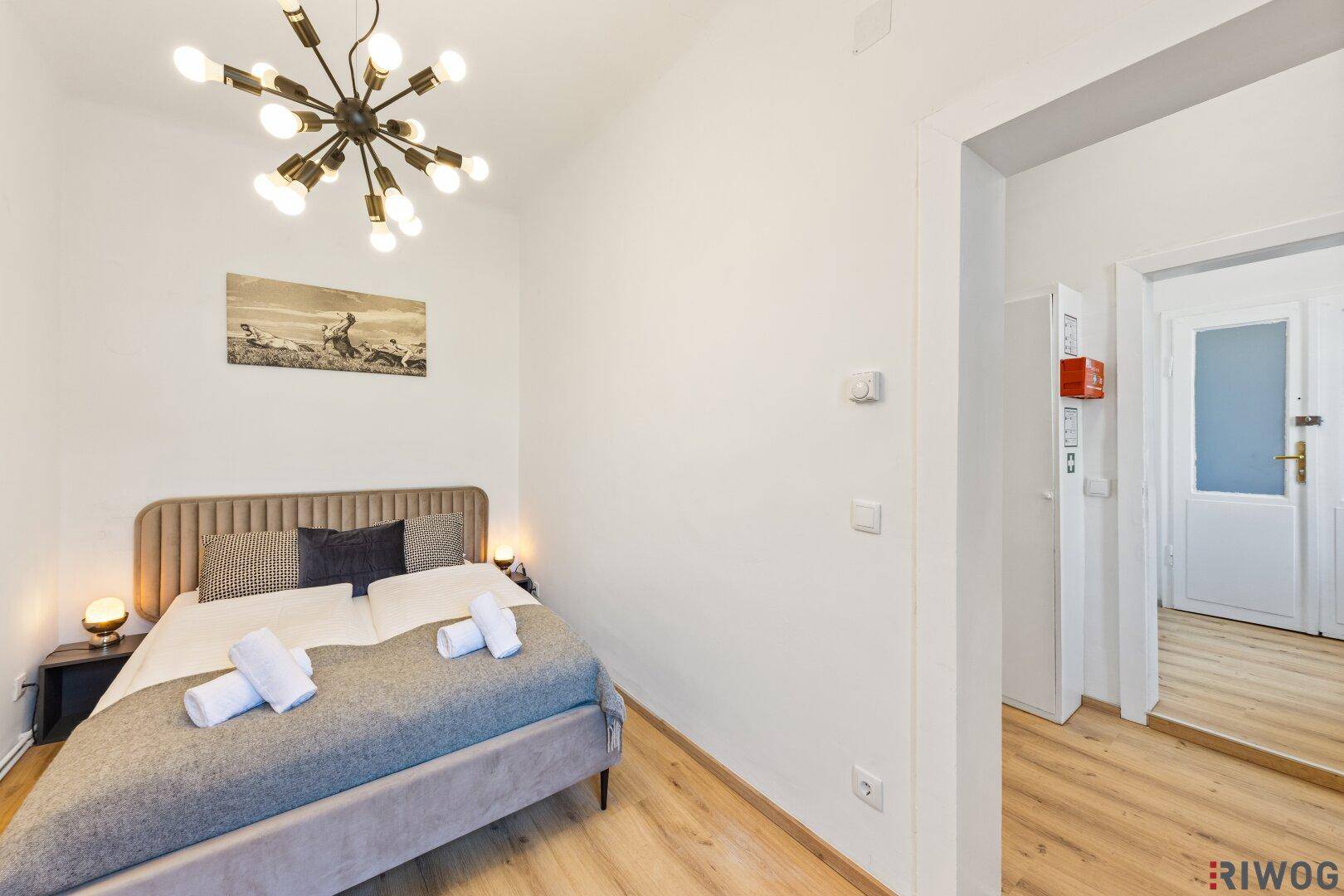 Schlafzimmer mit Einzelbett, Nachttischen und Zugang zum Flur.
