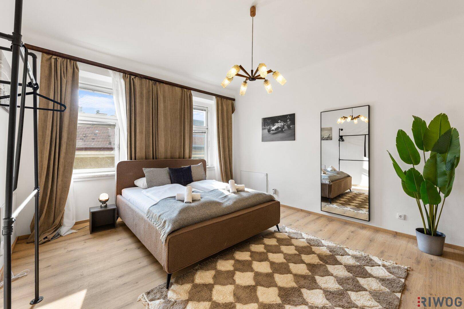 Helles Schlafzimmer mit Doppelbett, großem Spiegel und Holzboden.