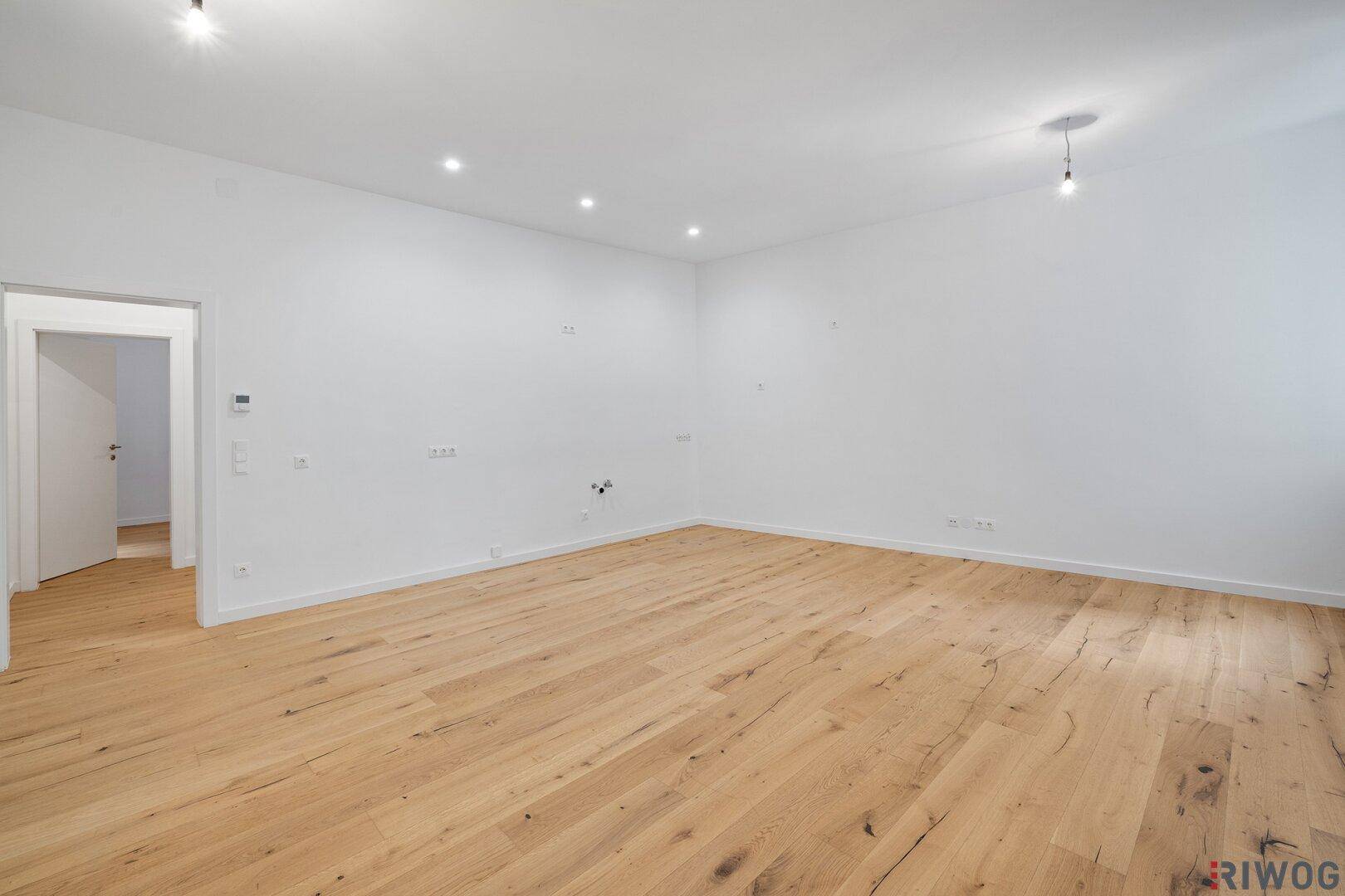 Geräumiges, unmöbliertes Wohnzimmer mit hellem Holzboden und viel Tageslicht.