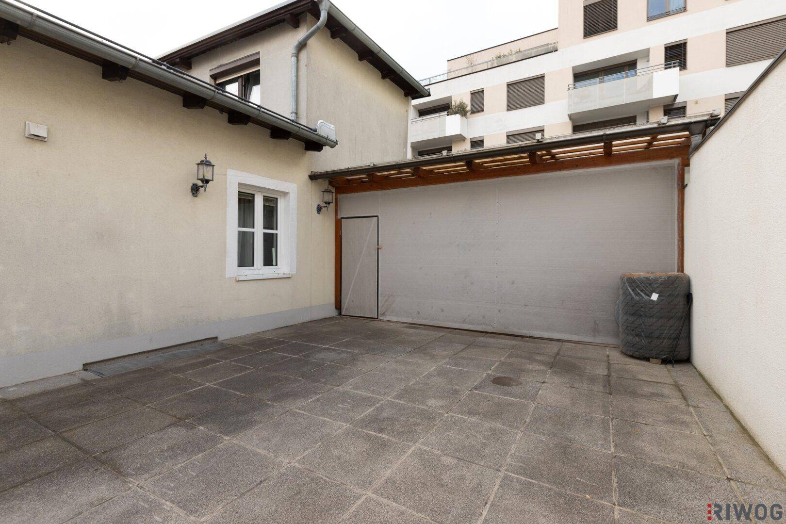 Gepflasterter Außenbereich mit Überdachung, ideal als Carport oder geschützter Sitzplatz im Freien.