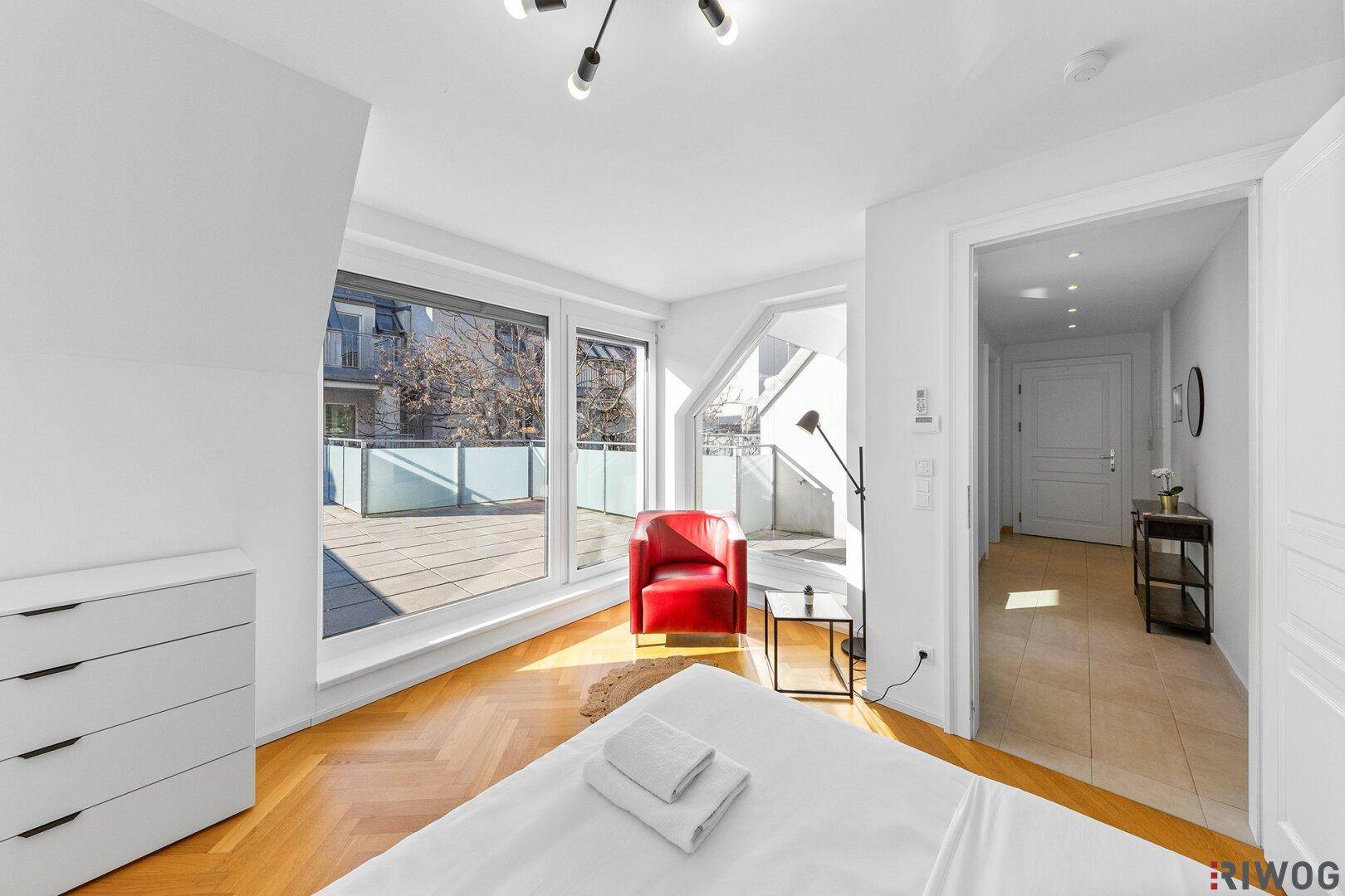 Helles Schlafzimmer mit Parkettboden, großen Fenstern und direktem Zugang zur Terrasse.