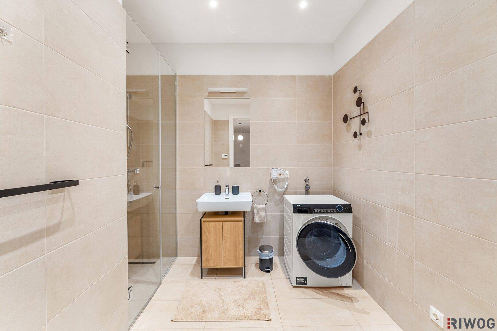 Modernes Badezimmer mit begehbarer Dusche, Waschbecken und Waschmaschine.