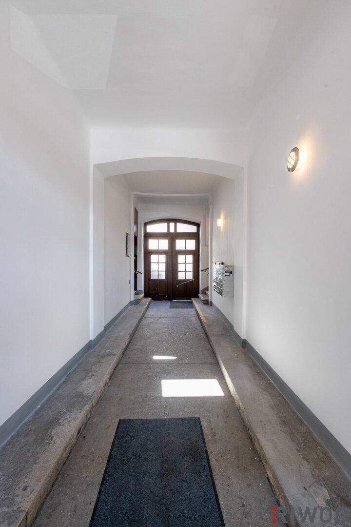 Eingangsbereich mit Rampe für barrierefreien Zugang und Holztüren am Ende des Ganges.