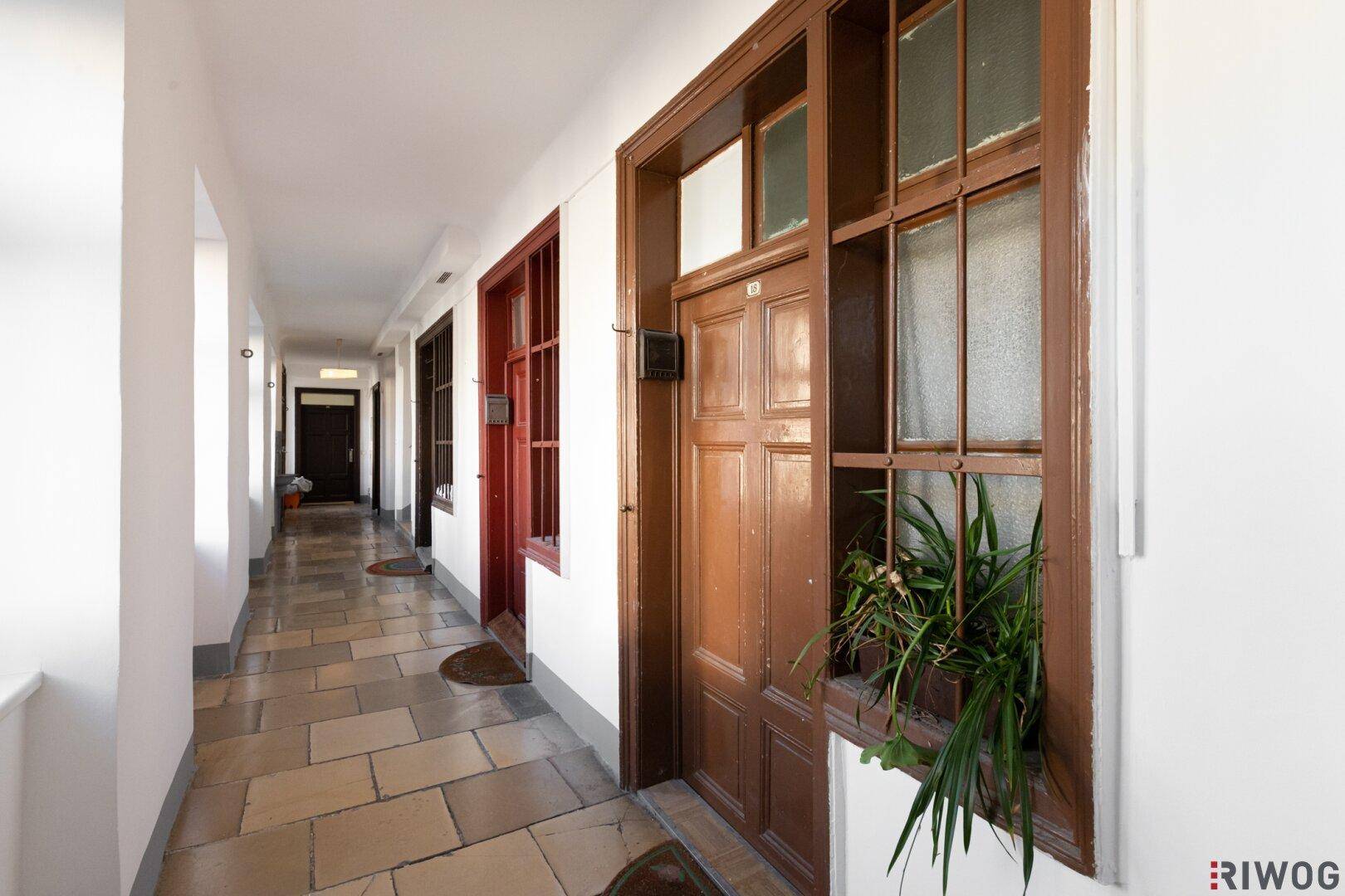 Heller Hausflur mit Fliesenboden und traditionellen Holztüren zu den Wohnungen.