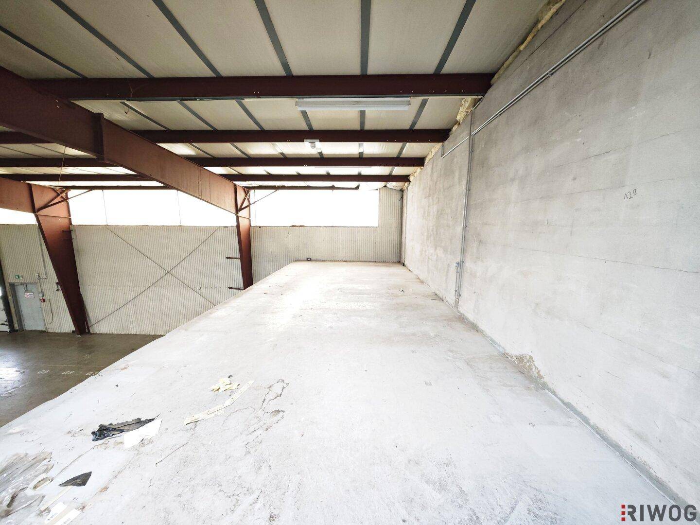 Großer, leerer Lagerraum mit Betonboden und hohen Decken, ideal für verschiedene Lagerzwecke.