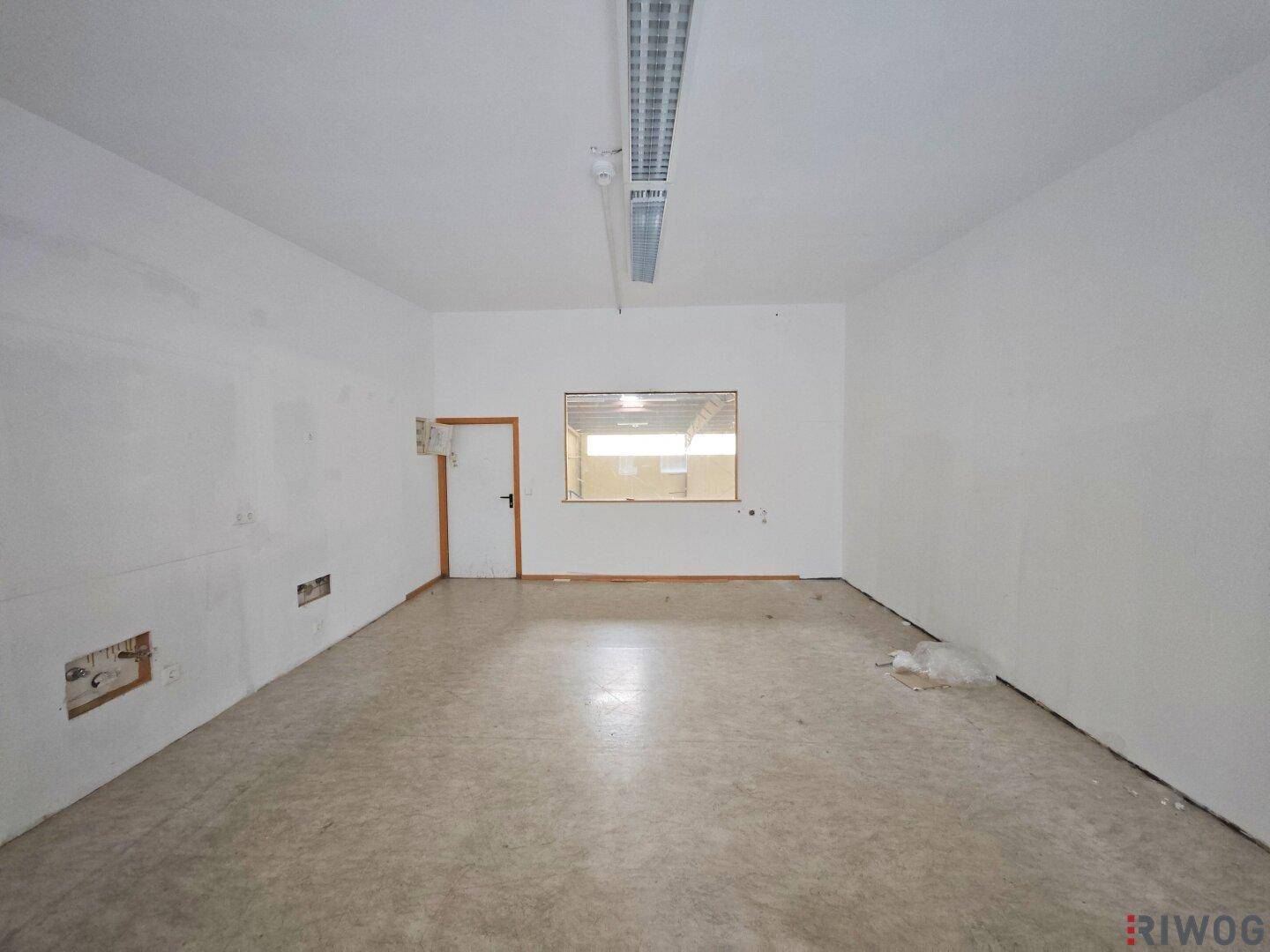 Leerer Büroraum mit weißen Wänden, einem Fenster und Linoleumboden, bereit zur individuellen Gestaltung.
