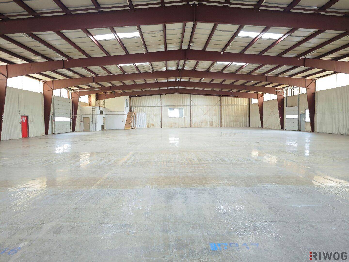Weitläufige Lagerhalle mit hohen Decken und robustem Betonboden, bereit für verschiedene gewerbliche Zwecke.