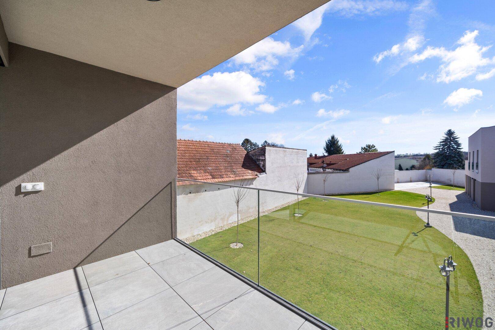Geräumiger Balkon mit Glasgeländer und weitem Blick über die umliegende Landschaft.