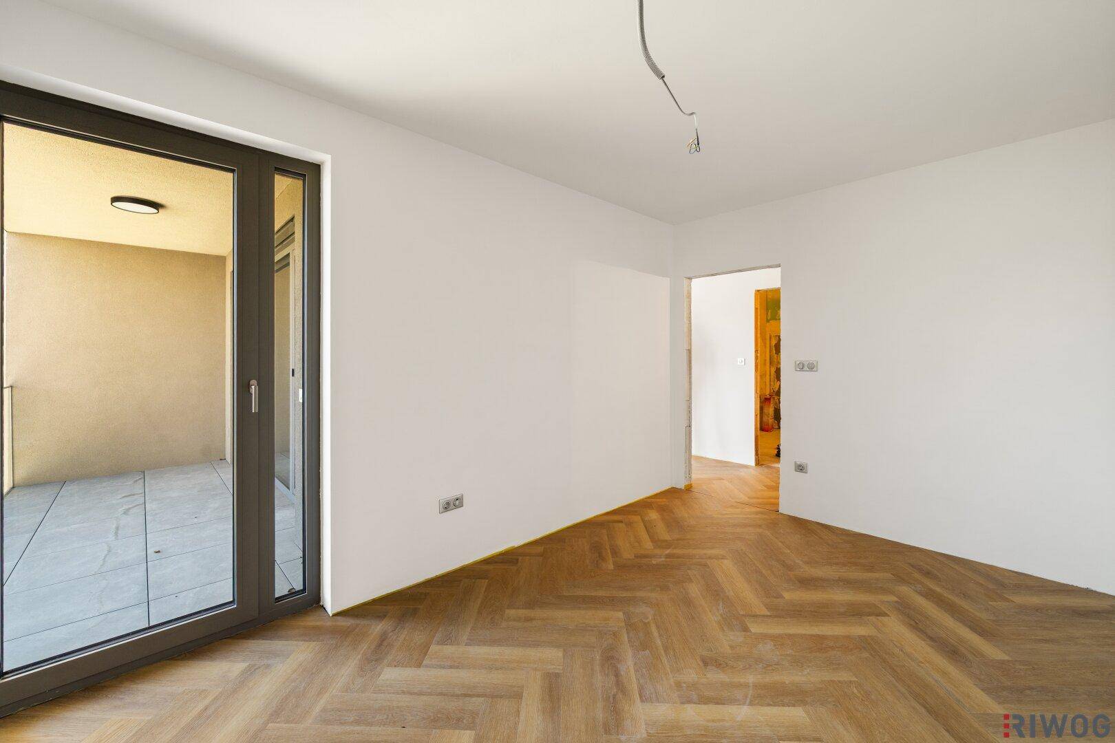 Schlafzimmer mit Fischgrätparkett und direktem Zugang zu einem privaten Balkon.