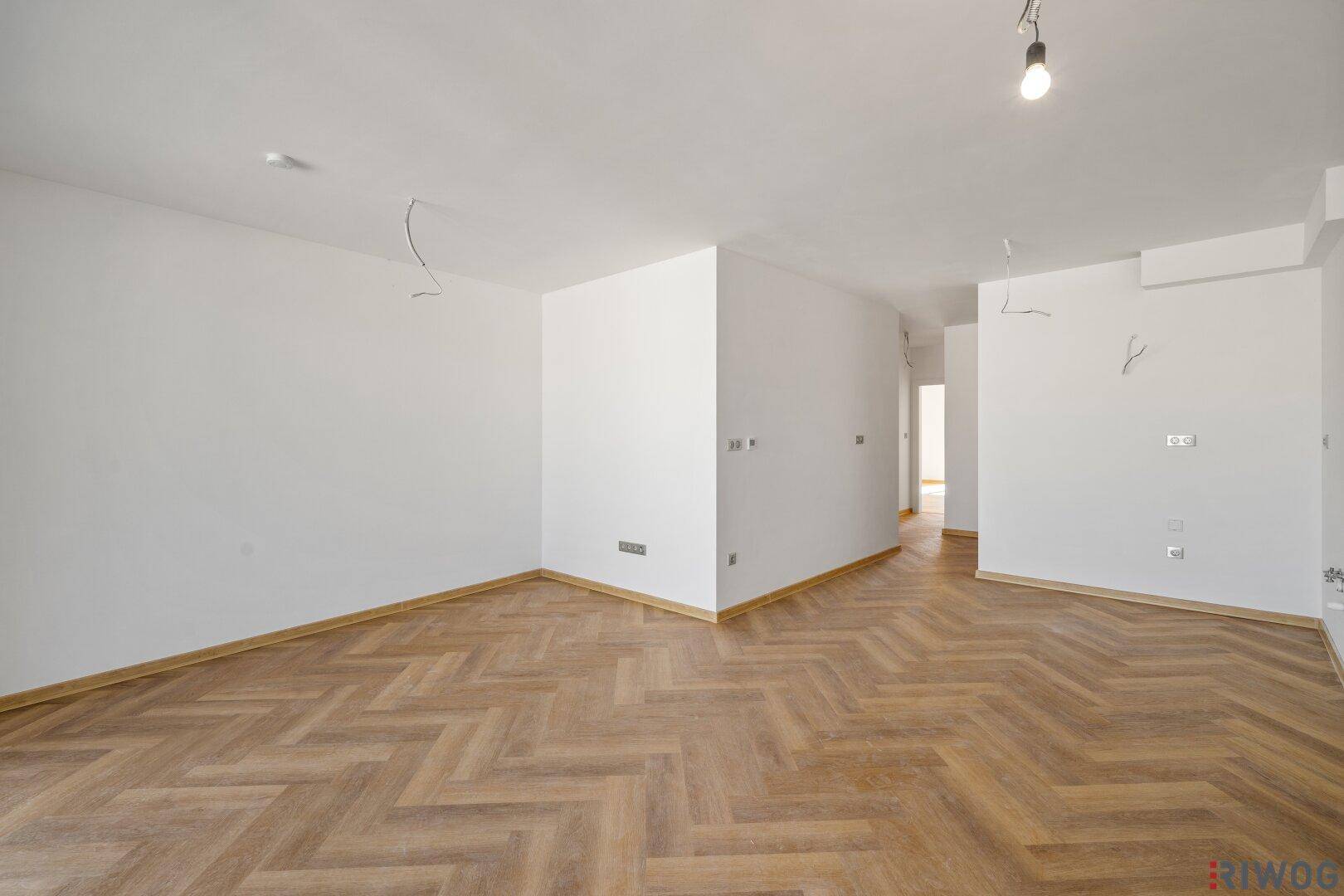 Geräumiger Wohnraum mit elegantem Fischgrätparkett und weitem Blick ins Grüne.