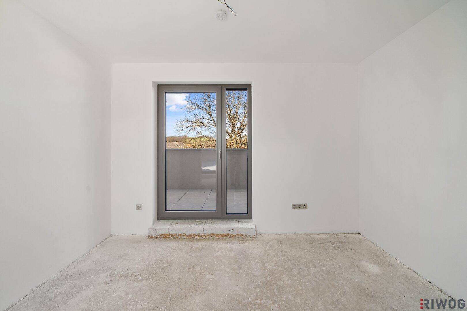 Unfertiges Zimmer mit Fenster und Blick auf Bäume, bereit für die individuelle Gestaltung.