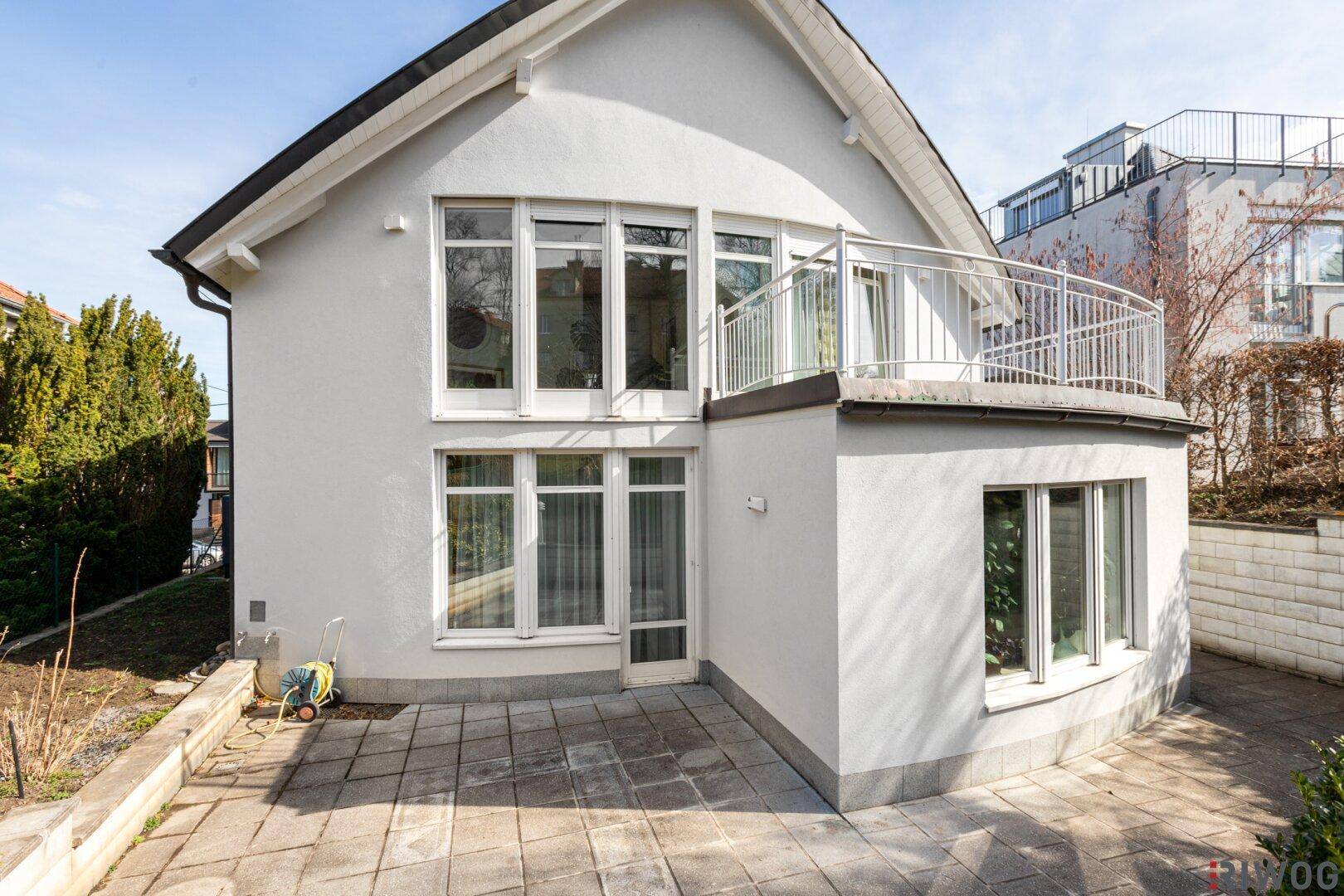 Rückseite des Hauses mit gepflasterter Terrasse und Zugang zum Gartenbereich.