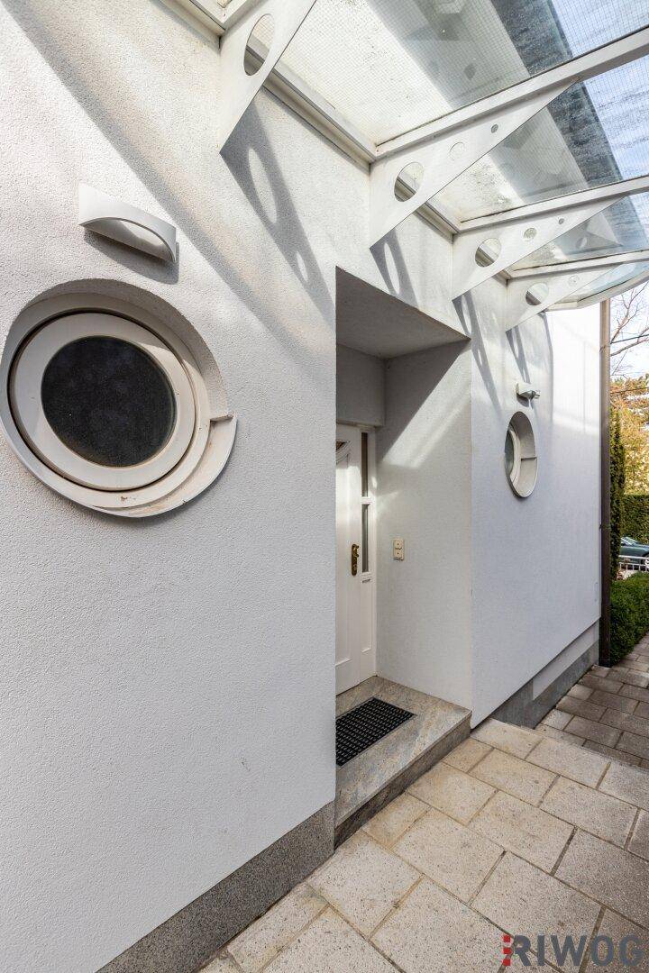 Eingangsbereich des Hauses mit moderner Glasüberdachung und runden Fenstern.