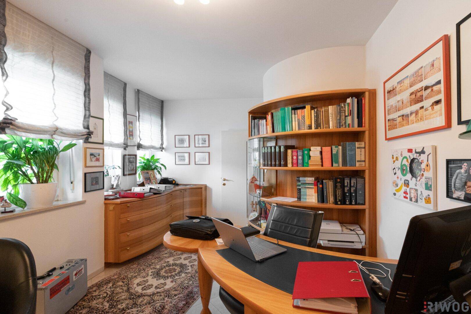 Helles Arbeitszimmer mit Holzmöbeln, Teppichboden und Blick ins Grüne.