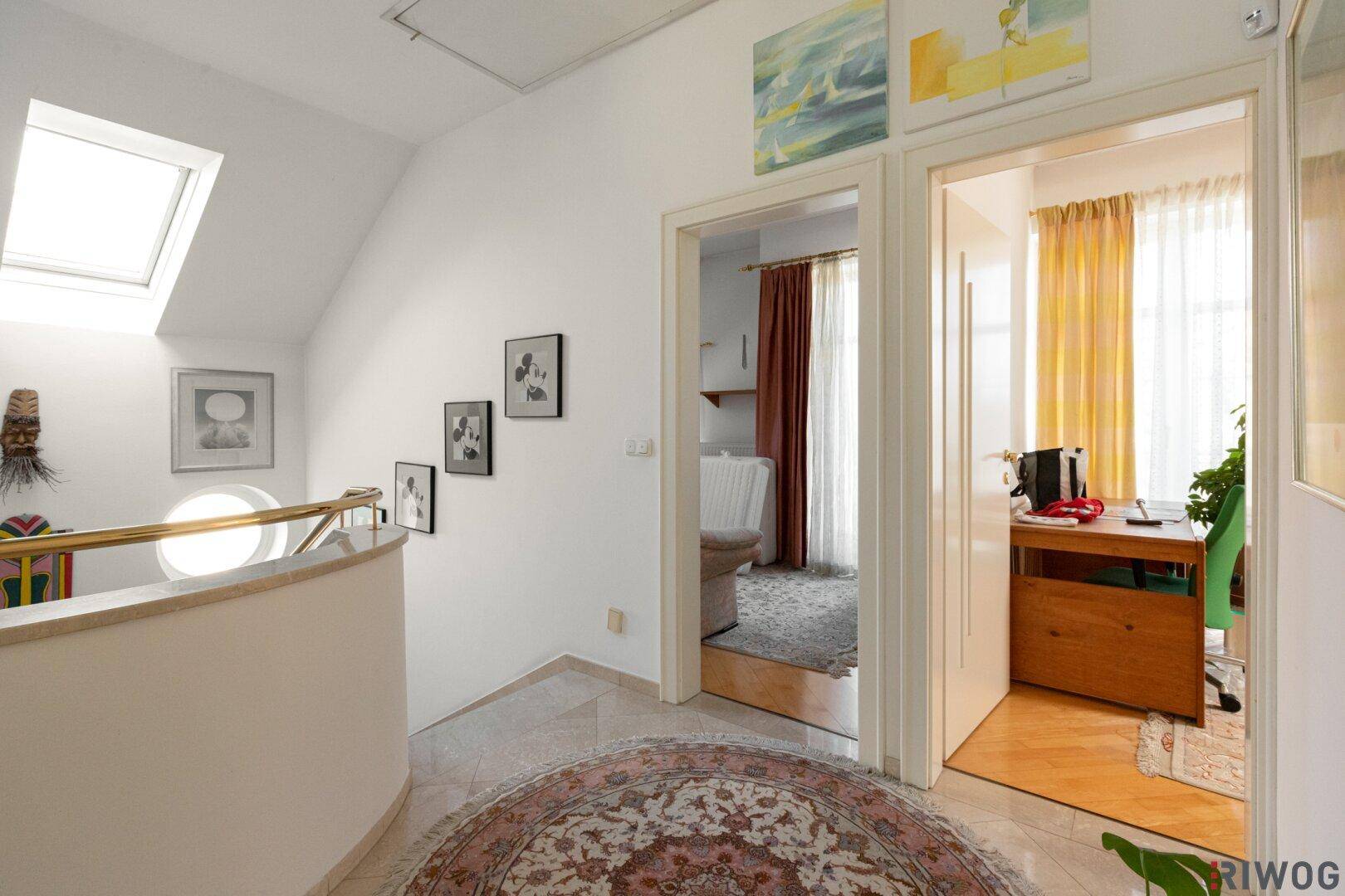 Heller Flur im Obergeschoss mit Dachfenster und Zugang zu weiteren Zimmern.