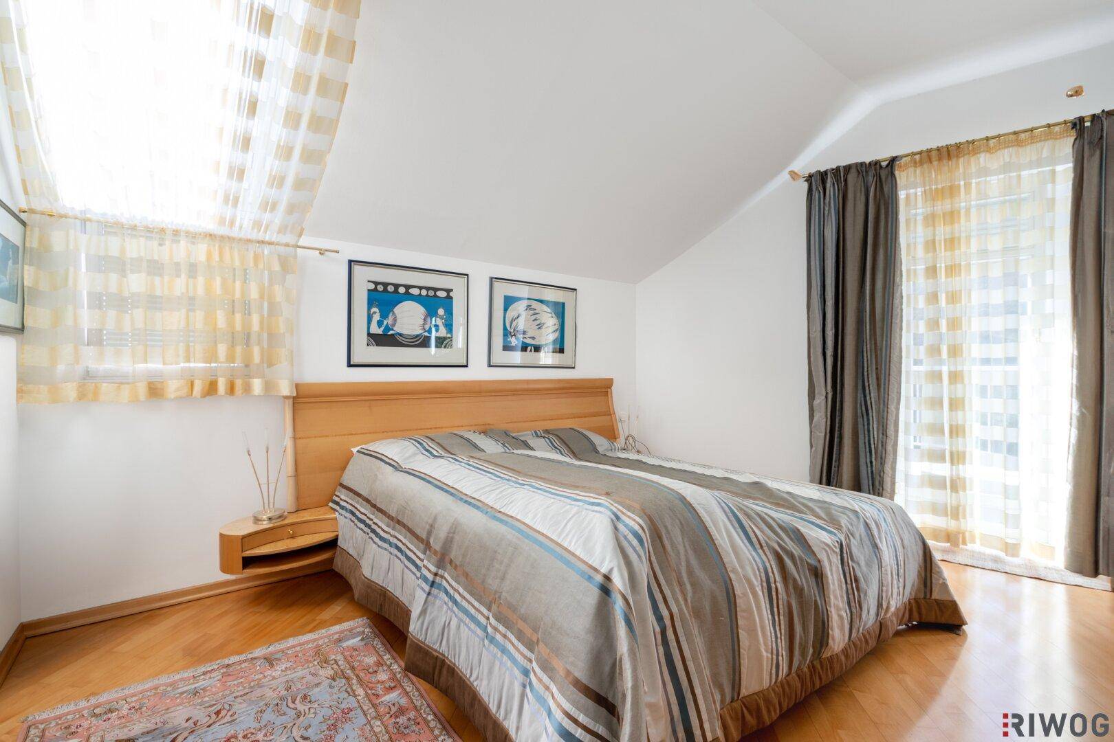 Schlafzimmer im Dachgeschoss mit Holzboden, Doppelbett und großen Fenstern.