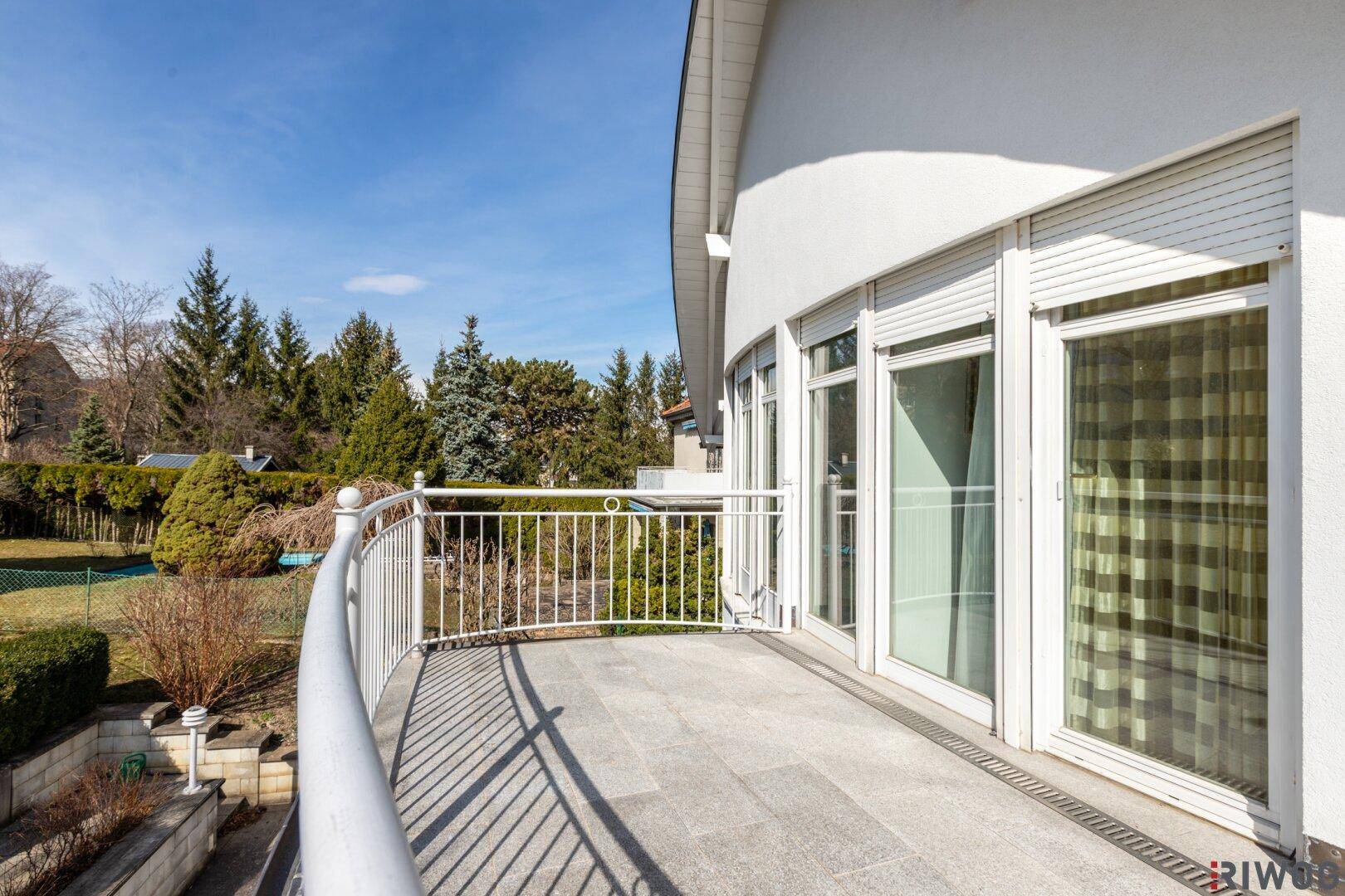 Großer Balkon mit Fliesenboden und Metallgeländer, ideal zum Entspannen im Freien.