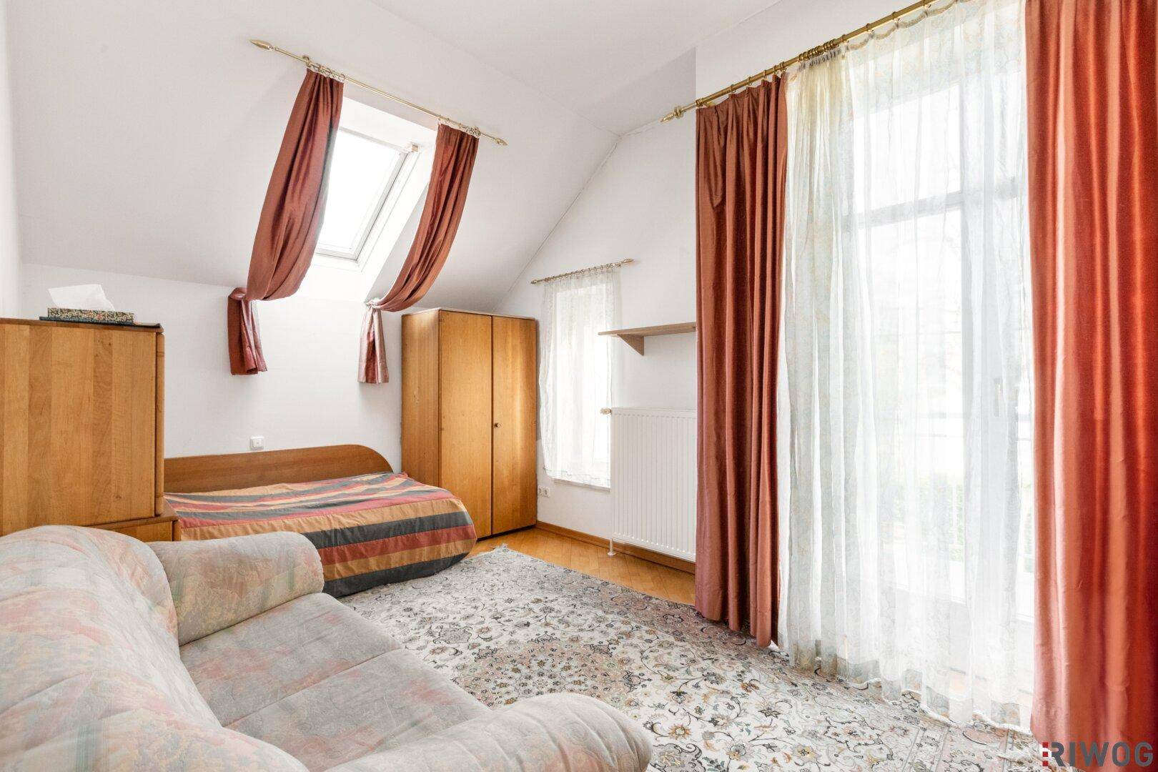 Gemütliches Schlafzimmer im Dachgeschoss mit Dachfenster und Teppichboden.