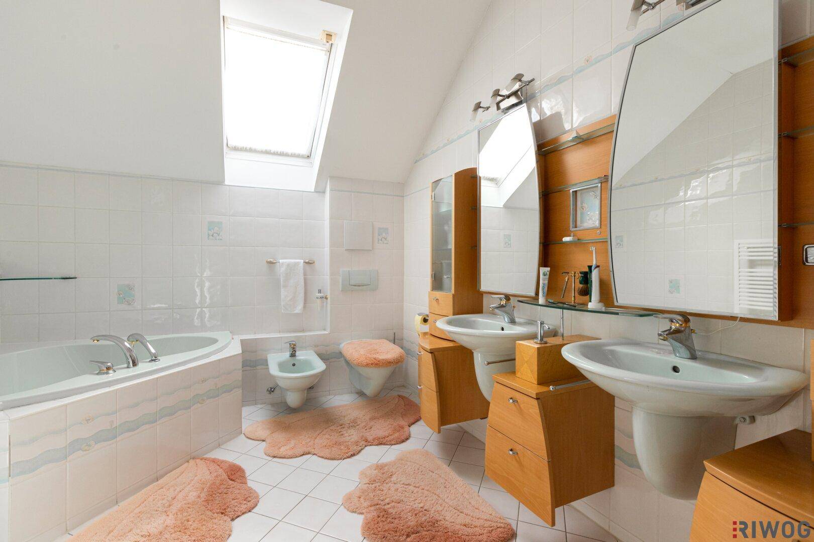 Geräumiges Badezimmer mit Doppelwaschbecken, Eckbadewanne und Dachfenster.