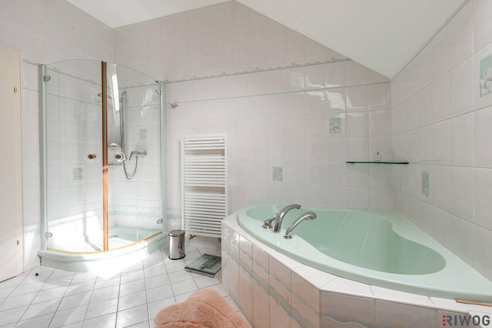 Badezimmer mit Eckbadewanne, Duschkabine und beheiztem Handtuchhalter.