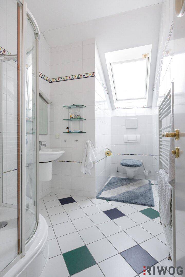 Helles Badezimmer mit Duschkabine, WC und Dachfenster für viel Tageslicht.