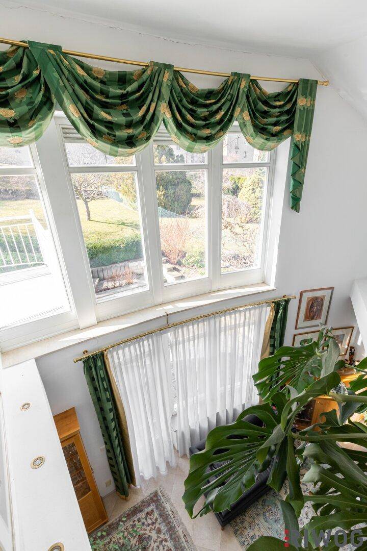 Große Fensterfront im Wohnzimmer mit Blick auf den gepflegten Garten und viel Tageslicht.