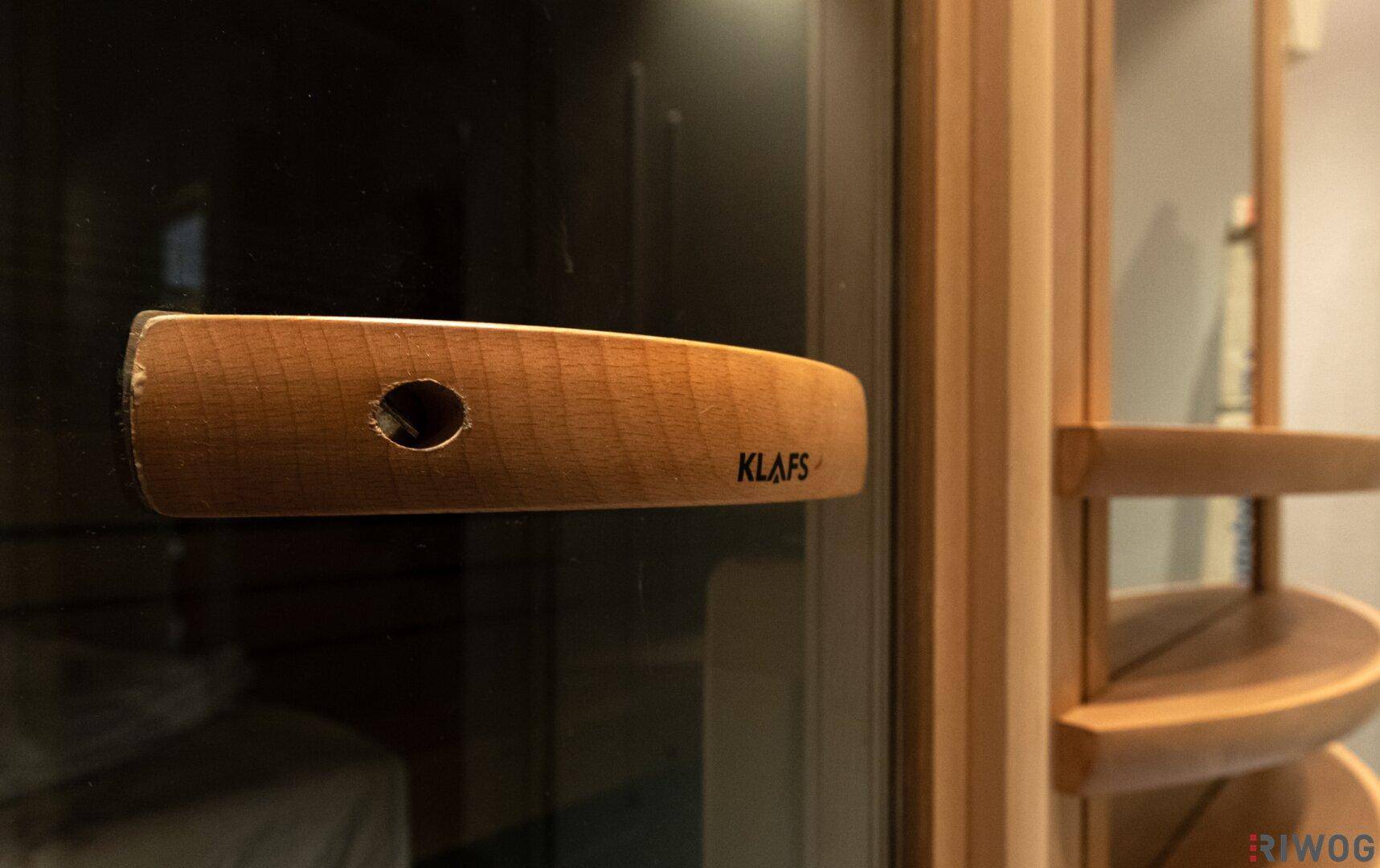 Detailansicht des Holzgriffs an der Saunatür mit Markenlogo.