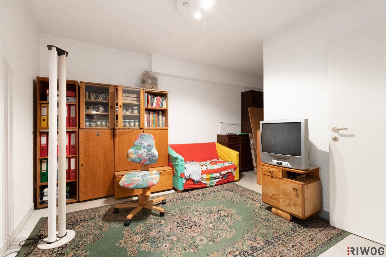 Vielseitig nutzbarer Raum im Kellergeschoss mit Teppich und Bücherregalen.