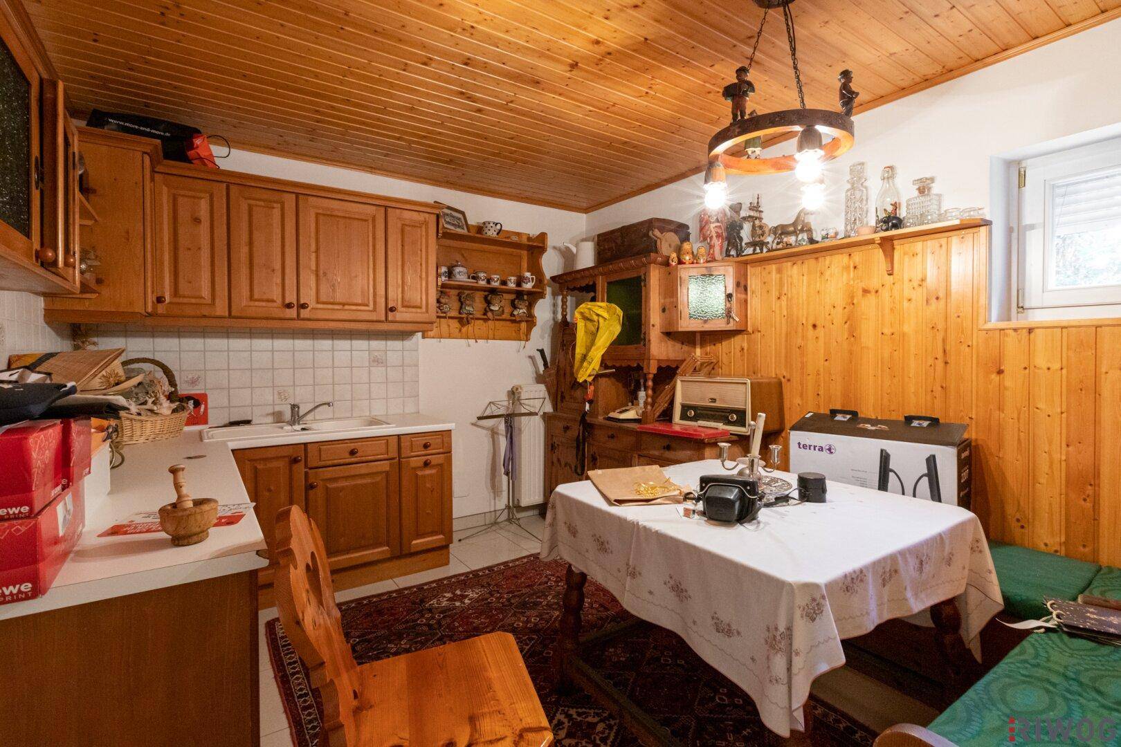 Rustikale Küche im Kellergeschoss mit Holzverkleidung und Essbereich.
