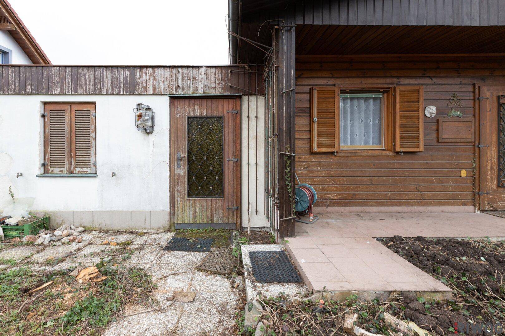 Detailansicht des Hauseingangs mit Holztür und angrenzender Holzverkleidung.