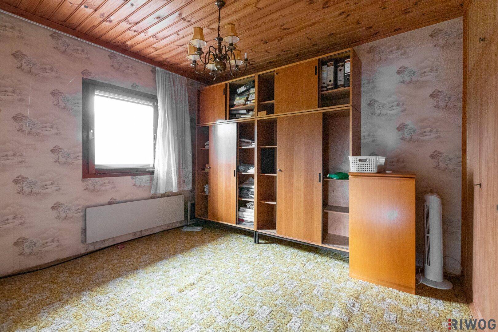 Schlafzimmer mit Holzdecke, Teppichboden und einem großen Einbauschrank.
