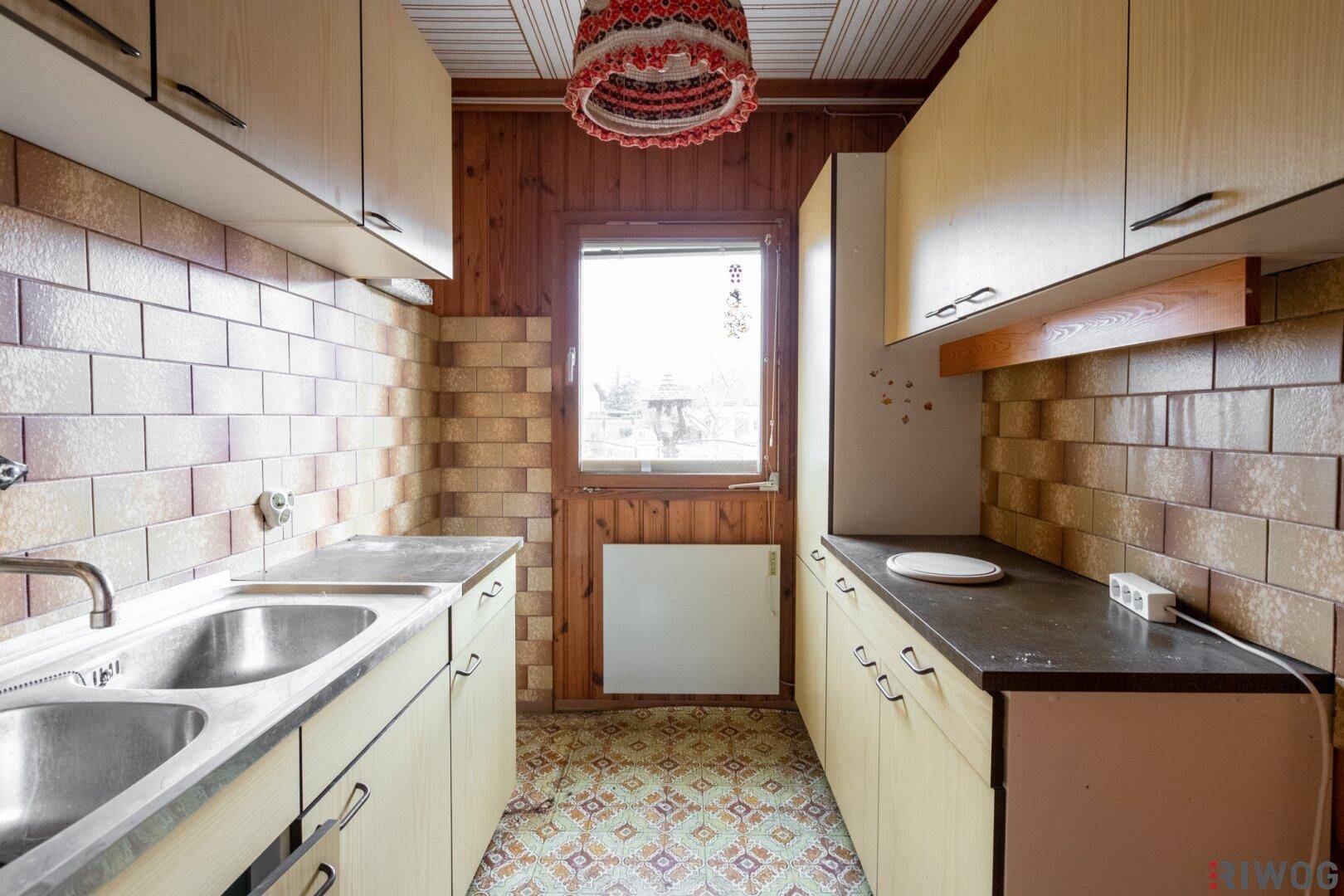 Küche im älteren Stil mit Holzvertäfelung, gefliestem Spritzschutz und doppelter Spüle.
