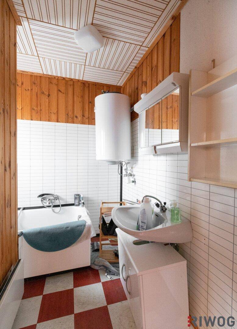 Badezimmer mit weiß gefliesten Wänden, Holzvertäfelung und einer Badewanne.