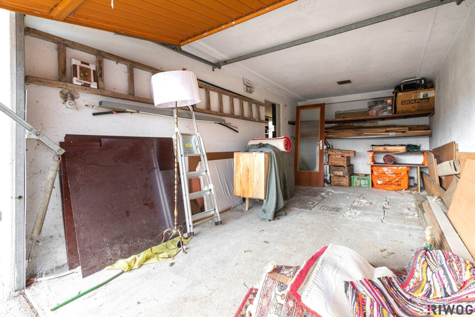 Geräumige Garage oder Abstellraum mit Betonboden und verschiedenen Lagergegenständen.