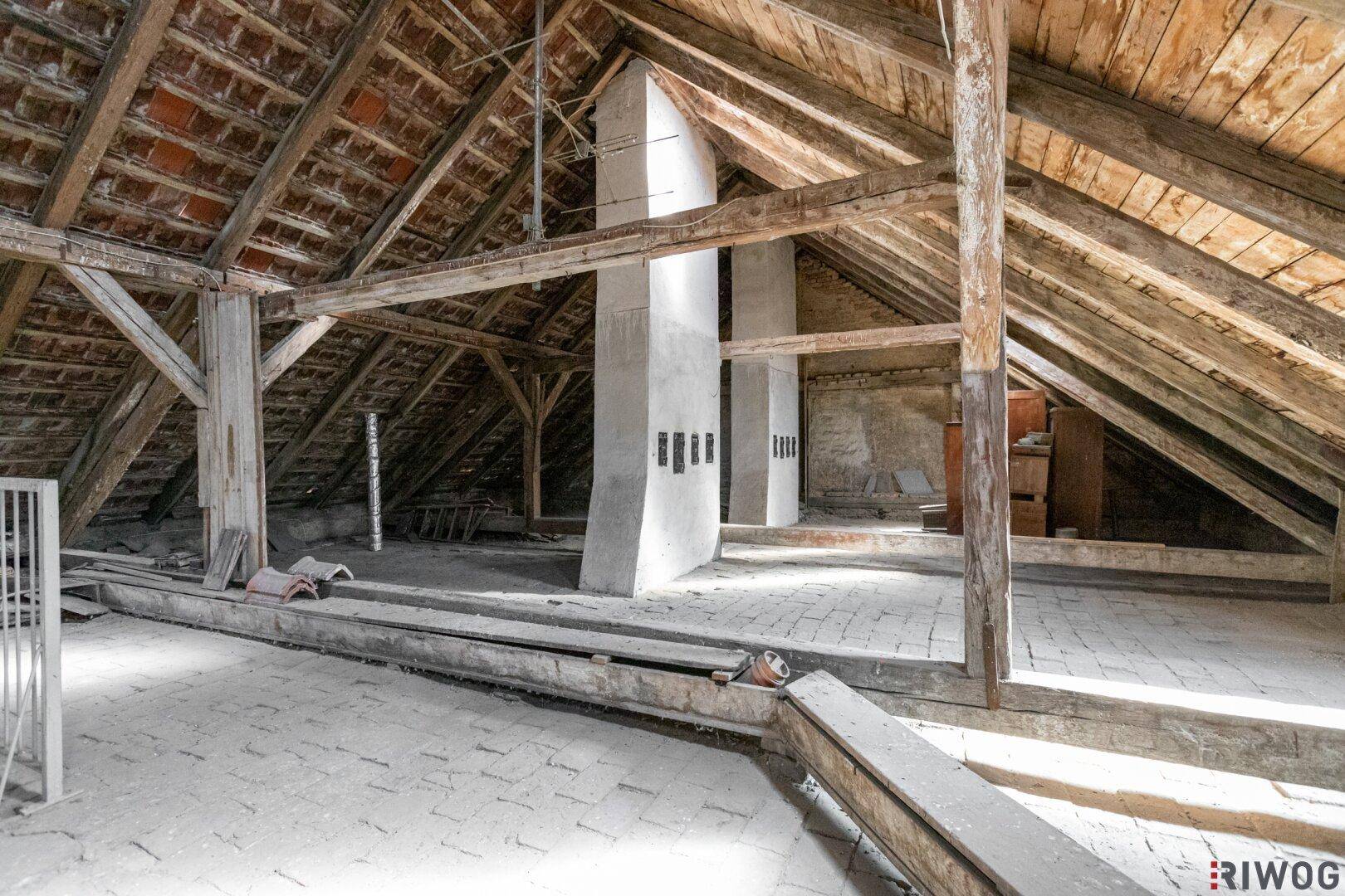 Großer Dachboden mit Holzdachstuhl und Ziegelboden, ideal für zukünftige Wohnraumnutzung.