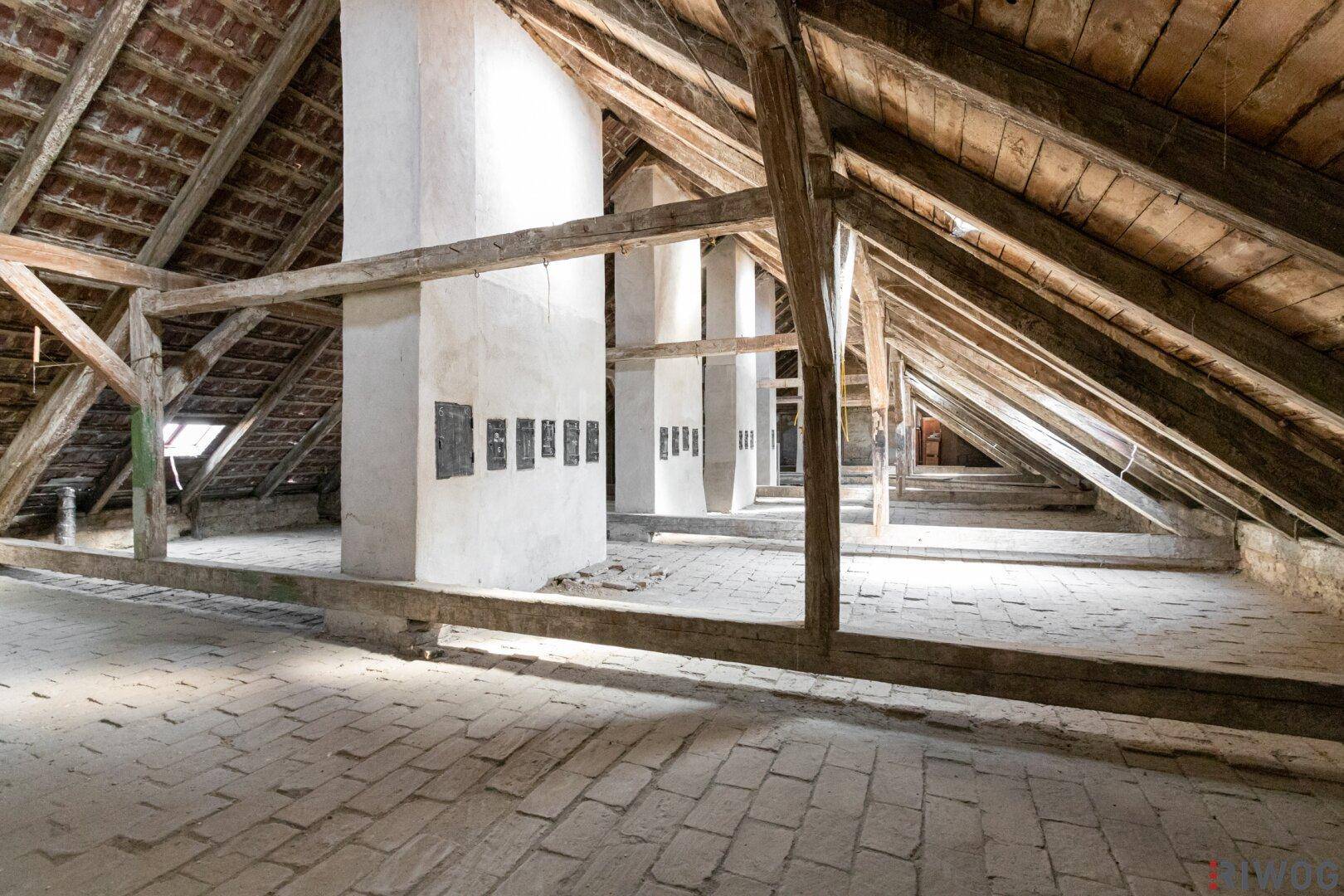 Weitläufiger Dachboden mit Holzdachstuhl und Ziegelboden, bietet Raum für kreative Gestaltung.