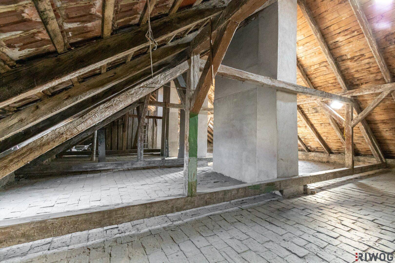 Geräumiger Dachboden mit sichtbaren Holzbalken und Ziegelboden, bietet viel Entwicklungspotenzial.