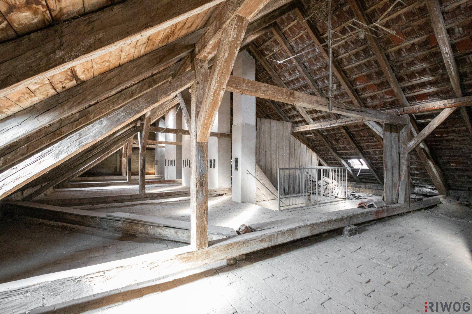 Dachboden mit Holzdachstuhl und Ziegelboden, bereit für die Umwandlung in Wohnraum.