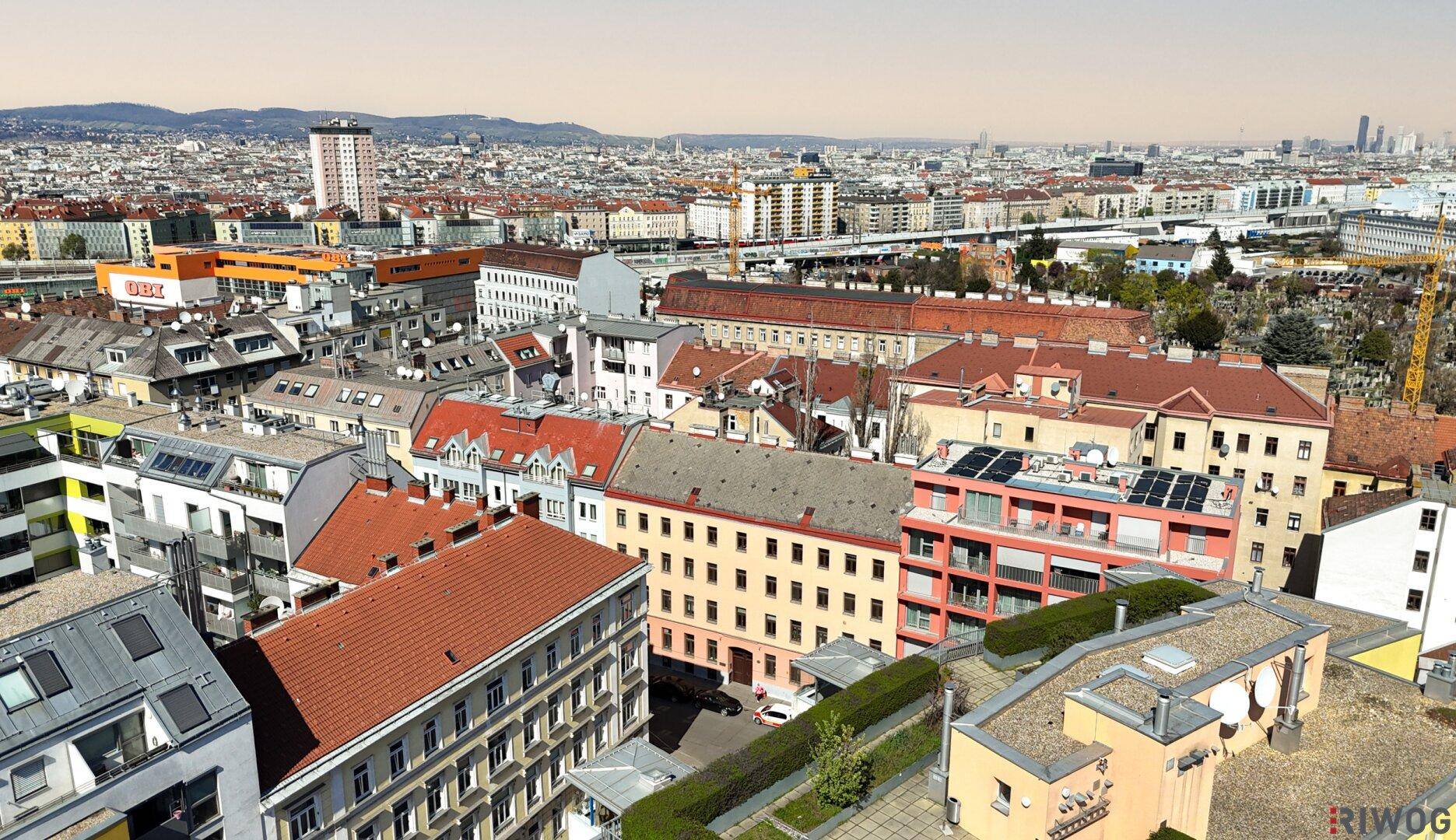 Weitläufiger Stadtblick mit verschiedenen Gebäudetypen und Dächern unter klarem Himmel.