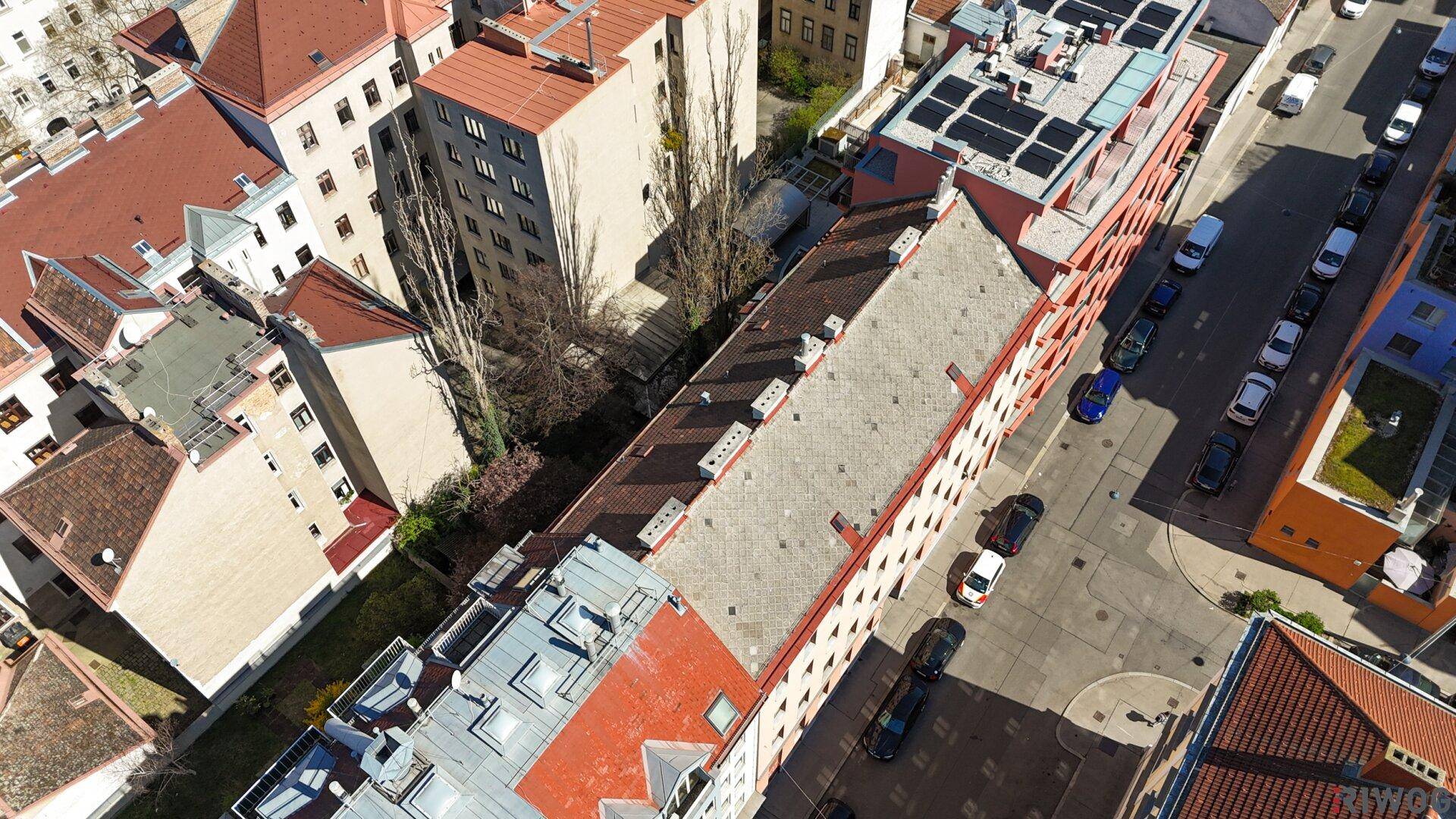 Luftaufnahme eines Wohnblocks mit Innenhof und angrenzenden Gebäuden in der Stadt.